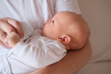 Bir baba üç aylık oğlunu kollarına alır..
