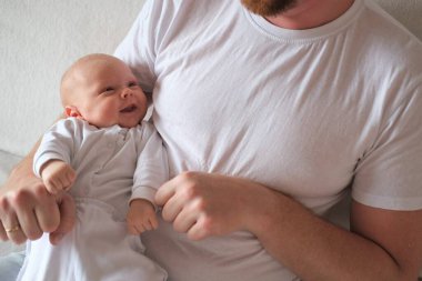 Bir baba üç aylık oğlunu kollarına alır..