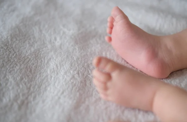 Babyfüße aus nächster Nähe auf dem Hintergrund einer weißen Decke. — Stockfoto