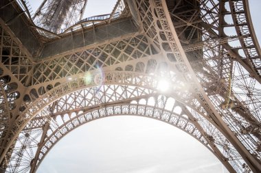 Eyfel Kulesi 'nin alışılmadık bir perspektifi var. Parlak güneş ışınları, açıklık metal yapısına doğru ilerler. Eyfel Kulesi 'nin bir parçası. Paris, Fransa. Seyahat kavramı.