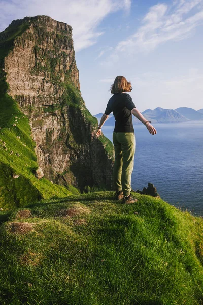 Red-haired hiker young girl looks at the ocean