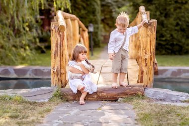 Küçük bir kız ve bir oğlan nehrin karşısındaki köprüde oturuyorlar. Bir kız elinde evcil bir tavşan tutuyor. Çocuklar birlikte gülümser ve oynarlar. Doğa yürüyüşü.