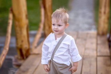 Küçük bir çocuk nehrin üzerindeki bir köprüde duruyor. Çocuk bunu düşündü. Çocuk neşelidir. Doğa yürüyüşü.