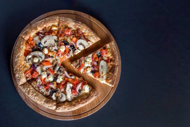 Sebzeli pizza, arka planda tahta kesim tahtasının üzerindedir. Bir parça ayrı. Mesaj için yer var. Yukarıdan görünüşü.