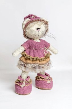 El yapımı oyuncak bir kedi. Beyaz arka planda örülmüş kedi. Bir oyuncak portresi. Oyuncaklar için giysi örüyorum. Kapatın. Amigurumi kedi oyuncağı. Tığ işi hayvanlar..