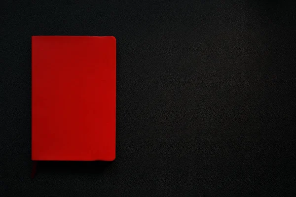 Siyah deri arka planda kırmızı defter. Defter sol köşede. Siyah arkaplanda kırmızı dikdörtgen
