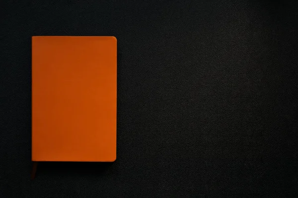 黒い革の背景にオレンジノート 左隅のノート — ストック写真