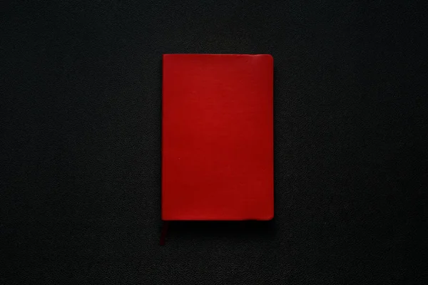 Siyah deri arka planda kırmızı defter. Defter ortada.