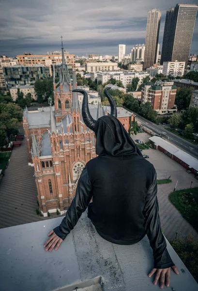 Siyah boynuzlu, modaya uygun bir iblis katedrale bakıyor..