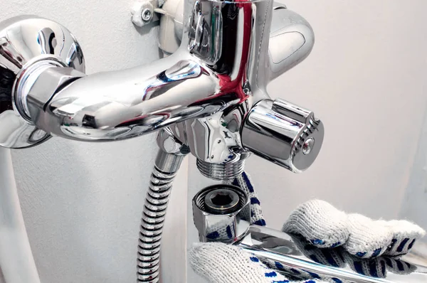 Eldivenli adamların elleri su musluğunu tamir ediyor. Yakın plan..