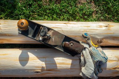 El uçağı ve eldivenler dışarıdaki nemli çam kütüklerinde yatıyor. Kütüklerin işlenmesi, ağaç kabuğunun temizlenmesi ahşap ürünlerin üretimi için süreçtir. Üst görünüm.