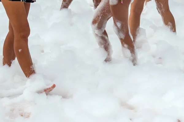 Foam party. White airy foam on the dance floor, many ladies dancing feet