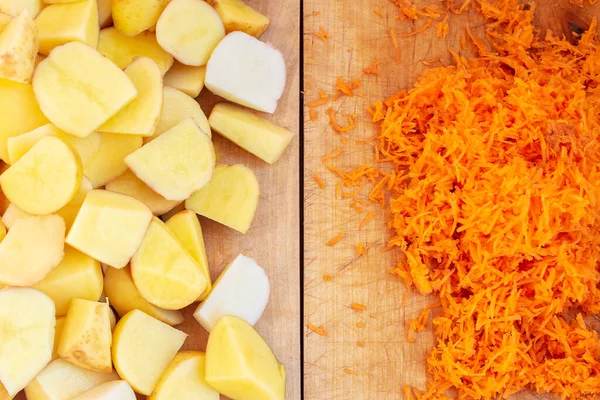 Çiğ patates ve havuç kesme tahtalarında kesilir. Organik Taze Sebzelerle Sağlıklı Yemek Malzemeleri. Üst görünüm.