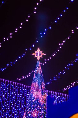 Geceleri modern Noel ağacı çelenklerinin rengarenk ışıkları. Film tahılları, yumuşak odak.