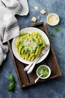 Penne rigate makarna parmesan peyniri ve fesleğen ile seramik tabak içinde gri vintage eski beton arka plan üzerinde bırakır. Seçici odak.