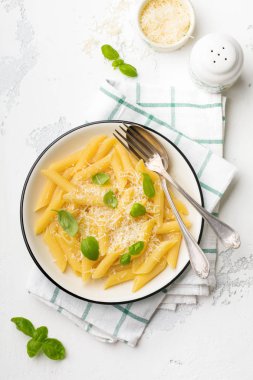 Penne rigate makarna parmesan peyniri ve fesleğen ile açık eski beton renkli seramik tabak içinde bırakır. Seçici odak.