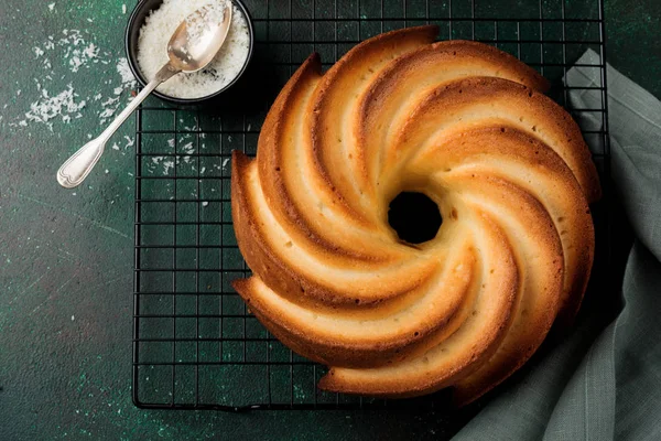 Şeker sır ve koyu yeşil eski beton zemin üzerine Hindistan cevizi ile kek. Seçici odak. Kopya alanı ile üstten görünüm.