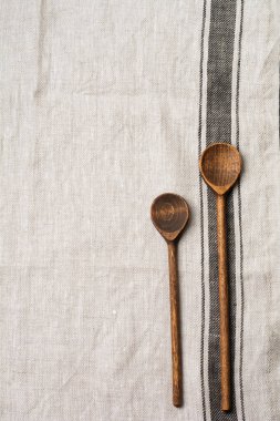 Doku kahverengi şerit ve iki ahşap eski vintage kaşık ile gri kumaş. Kopya alanı ile üstten görünüm.