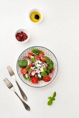Domates, ıspanak yaprakları, kırmızı soğan ve beyaz peynirli salata hafif bir seramik tabak. Seçici odak. Üstten görünüm.