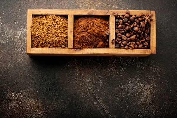 Food background with three kinds of coffee: beans, milled, instant in wooden box on old concrete brown background. Rustic stile. Selective focus. Top view.
