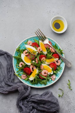 Roka, salatalık, domates, yumurta ve karides salatası soya sosu seramik plaka üzerinde. Seçici odak. Üstten görünüm.