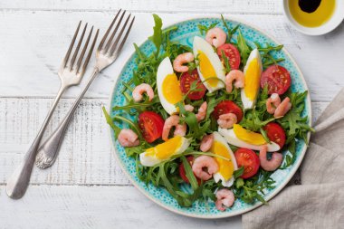 Roka, salatalık, domates, yumurta ve karides salatası soya sosu seramik plaka üzerinde. Seçici odak. Üstten görünüm.