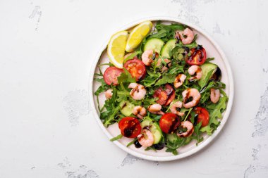 Roka, salatalık, domates ve karides salatası soya sosu bir seramik tabak. Seçici odak. Üstten görünüm.