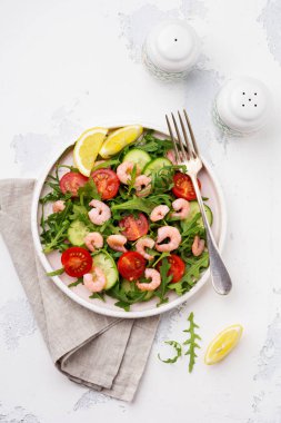 Roka, salatalık, domates ve karides salatası soya sosu bir seramik tabak. Seçici odak. Üstten görünüm.