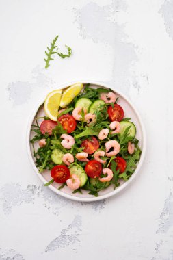 Roka, salatalık, domates ve karides salatası soya sosu bir seramik tabak. Seçici odak. Üstten görünüm.