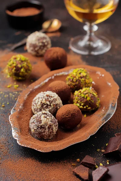 Ev yapımı koyu çikolata truffles kakao tozu, Antep fıstığı, badem koyu kahverengi arka plan doku içinde çeşididir. Üstten görünüm, kopya alanı.