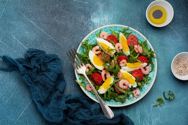 Roka, salatalık, domates, yumurta ve karides salatası soya sosu seramik plaka üzerinde. Seçici odak. Üstten görünüm.