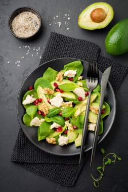 Taze yararlı vejetaryen sağlıklı avokado, ıspanak, nar taneleri, ceviz, safran, biber ve ricotta Salata siyah arka plan üzerine. Seçici odak. Üstten Görünüm. Metin için yer kopyalayın.