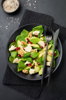 Taze yararlı vejetaryen sağlıklı avokado, ıspanak, nar taneleri, ceviz, safran, biber ve ricotta Salata siyah arka plan üzerine. Seçici odak. Üstten Görünüm. Metin için yer kopyalayın.