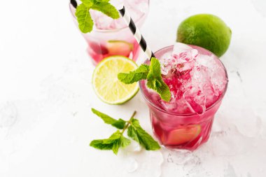 Kırmızı yaz içki buz, kireç, ahududu ve açık renkli şurubu ile soğutma. Seçici odak.