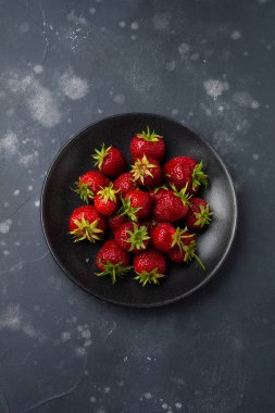 Karanlık eski beton zemin üzerine siyah plaka üzerinde taze çilek. Üstten görünüm.