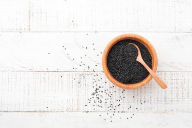 Siyah susam Beyaz ahşap zemin üzerinde bir bambu kasede. Üstten görünüm.