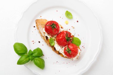 Pişmiş domates, sarımsak, zeytinyağı ve beyaz zemin üzerine Lor peynir sandviç. İtalyan mutfağı. Üstten görünüm.