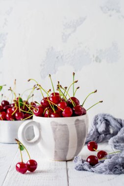 Hafif ahşap eski arka plan üzerinde vintage seramik Kupası'nda taze kiraz çilek.