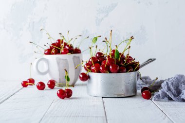 Hafif ahşap eski arka plan üzerinde rustik alüminyum tencerede taze kiraz