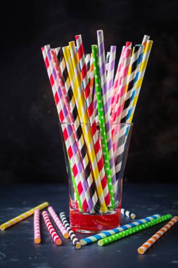 Çok renkli kağıt kokteyl ya da çöp için cam kavanoza koyu arka plan üzerinde rulo. Seçici odak.