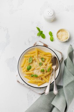 Penne rigate makarna parmesan peyniri ve fesleğen ile açık eski beton renkli seramik tabak içinde bırakır. Seçici odak
