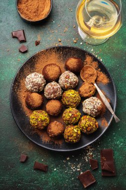 Ev yapımı koyu çikolata truffles kakao tozu, Antep fıstığı, badem koyu kahverengi arka plan doku içinde çeşididir. Üstten görünüm, kopya alanı.