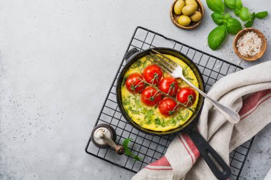 Frittata roka, patates ve domates eski taş tablo arka demir tavada. Üstten görünüm.