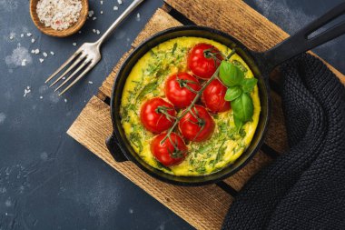 Frittata roka, patates ve domates eski taş tablo arka demir tavada. Üstten görünüm.