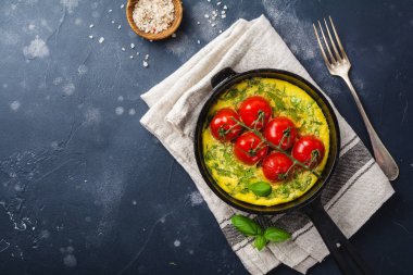 Frittata roka, patates ve domates eski taş tablo arka demir tavada. Üstten görünüm.