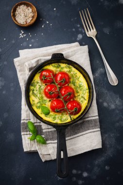 Frittata roka, patates ve domates eski taş tablo arka demir tavada. Üstten görünüm.