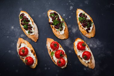 Barbunya, pişmiş domates, sarımsak, zeytinyağı ve lor peyniri koyu arka plan üzerinde çeşitli sandviçler. Üstten görünüm.