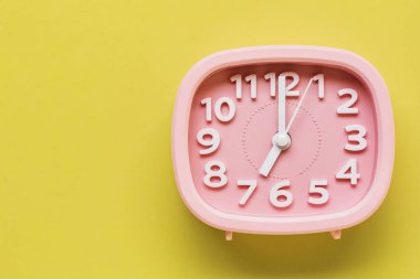 Pembe çalar saat sarı yüzey zemin üzerine yalan. Üstten görünüm. 