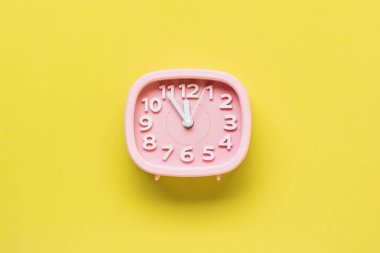 Pembe çalar saat sarı yüzey zemin üzerine yalan. Üstten görünüm. 