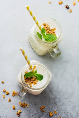 Muz smoothie granola, Kuruyemiş ve gri beton zemin üzerine nane. Üstten görünüm.